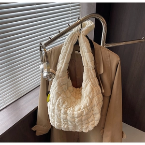 Close-up of white quilted cloud bag with textured fabric and yellow side label detail