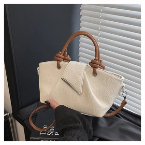 Close-up of beige lychee grain leather tote with a brown round handle and metal trim