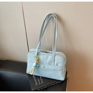 Dettaglio della borsa tote azzurra con tasca frontale a scatto e ciondolo a stella