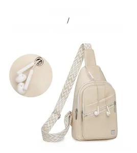Detail of exterior earphone jack on cream crossbody bag with geometric pattern strap