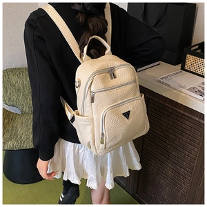 Detail view of a beige textured PU leather mini backpack showing zippers and side pockets