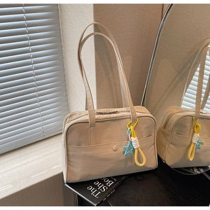 Dettaglio della borsa tote beige con tessuto strutturato, tasca esterna e ciondolo a stella