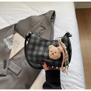 Detail view of plaid hobo bag with teddy bear charm and colorful rope pendant