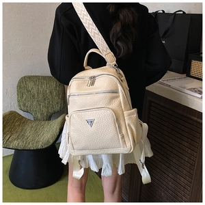 Detail view of cream textured backpack with wide patterned shoulder strap and metal logo