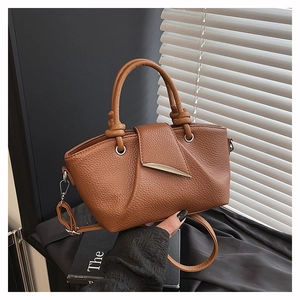 Detail of caramel lychee grain leather tote bag with asymmetric flap and silver moon buckle