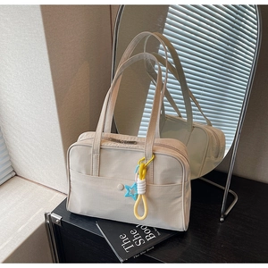 Vista dettagliata della borsa tote in tela bianco avorio con tasca frontale e ciondolo