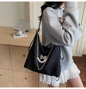 Détail du sac noir à pois avec breloque papillon en métal et chaîne de perles chic