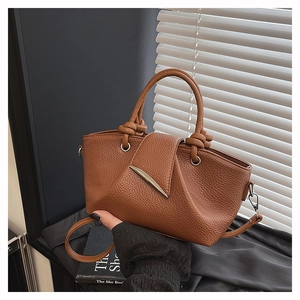 Detailed view of caramel lychee leather tote bag featuring knot handles and silver metal hardware
