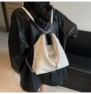 Détail du sac bandoulière blanc texturé avec chaîne argentée et perle sur un mannequin