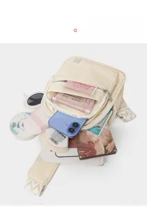Detail view of large capacity cream crossbody bag with phone, sunglasses, and notebook