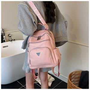 Close-up of pink pebbled leather backpack with metal logo and geometric strap detail