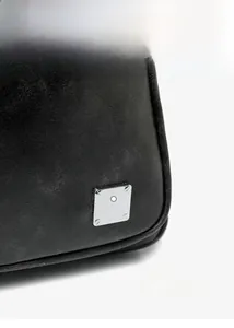 Detailed close-up of black textured fabric with silver square metal buckle accent