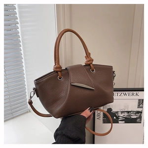 Detail of lychee pattern leather bucket bag with brown contrast strap and metal buckle