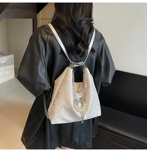 Détail d'un sac à dos blanc marbré avec chaîne argentée et décoration de perles