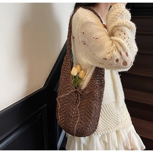 Detail of hollow-out knit tote bag in brown featuring a crochet texture and bow knot