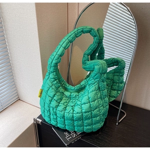 Detail of green quilted puffer handbag with textured finish and fashion label tag