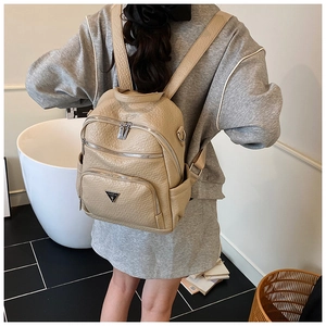 Macro view of beige lychee pattern faux leather backpack with multiple zipper pockets