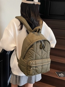Olive green quilted backpack with lightweight padded fabric shown from a side back view