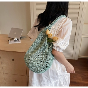 Detailed close-up of light green knit tote bag with a floral tulip accent decoration