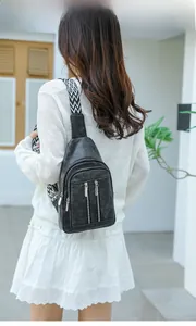 Close-up of black PU leather crossbody bag with geometric woven strap on model