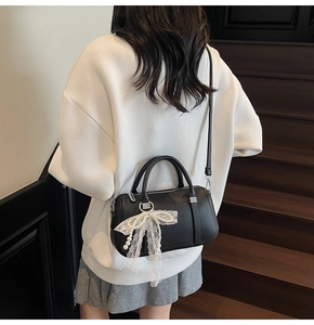 Detailed close-up of a black lychee texture Boston bag with lace and pearl bow charms