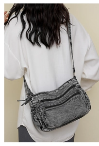 Détail du sac bandoulière en denim délavé gris avec plusieurs poches porté par le modèle