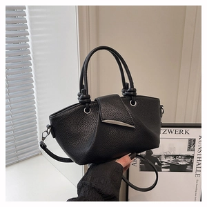 Detail of black lychee grain leather tote bag with silver clasp and knotted handle