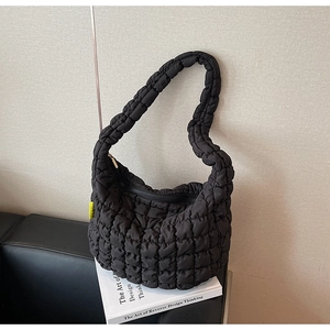 Detail of black quilted cloud bag with fluffy texture and yellow side label detail