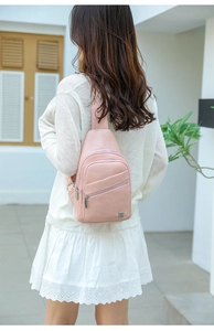 Close-up of pink leather crossbody chest bag with woven strap and multiple zipper pockets