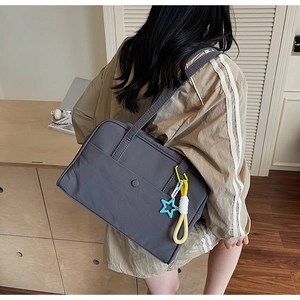 Grande borsa tote in tela grigio scuro con ciondolo a stella indossata da una modella