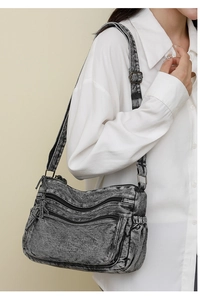 Détail du sac bandoulière en denim lavé avec plusieurs poches zippées et sa texture