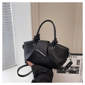 Close-up of black lychee-textured leather bucket bag with silver metal leaf-shaped buckle