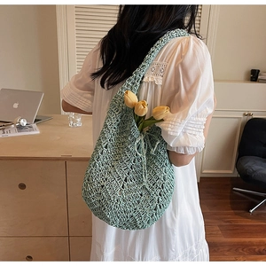 Close-up of mint green hand-woven hollow knit shoulder bag with crochet diamond texture