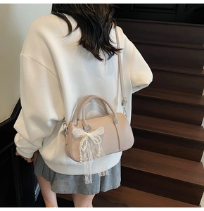 Detail of light pink pebble leather bowling bag with lace bow and pearl charm pendant