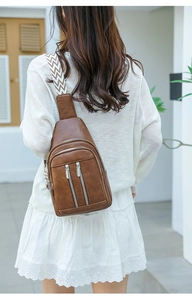 Rear view of model wearing a brown leather crossbody bag with woven patterned strap