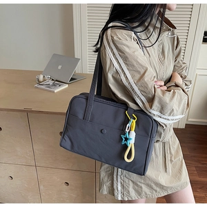 Dettaglio della borsa tote in tela grigio scuro con ciondolo a stella colorato a spalla