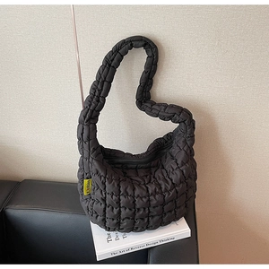 Detail of black quilted cloud bag texture and yellow 'Fashion' woven label accent