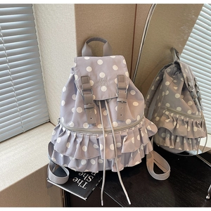 Detail of light purple polka dot backpack featuring ruffle trim and magnetic strap closure