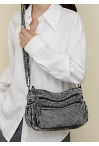 Détail d'un sac bandoulière vintage en denim gris délavé avec plusieurs poches zippées