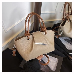 Close-up of lychee grain leather handbag with knot handle and silver metal buckle