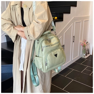 Detail of mint green textured leather backpack with silver hardware on a female model