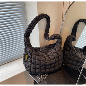 Detail of black quilted puffer bag with puffy texture and yellow side label accents