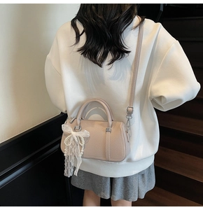 Detail of light pink lychee texture leather bag with lace bow and pearl chain charm