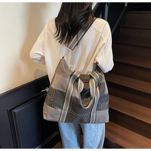 Detail of checkered canvas tote bag showing textured stitching and striped woven strap