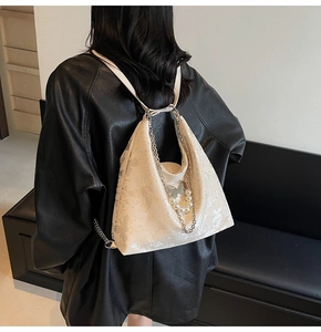 Détail de la texture florale sur sac à dos blanc avec chaîne argentée et pendentif perle