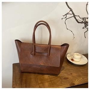 Close-up of a vintage brown tote bag with retro buckle and distressed leather texture
