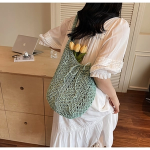 Detail of light green hollow knit tote bag featuring diamond pattern and drawstring
