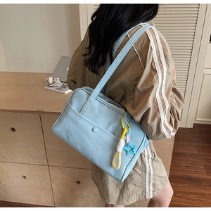 Dettaglio borsa tote in tela azzurra con ciondolo a stella e nappina intrecciata decorativa