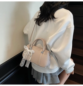 Detail of lychee pattern handbag featuring white lace bow and pearl pendant decoration