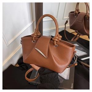 Detail of caramel lychee grain leather tote bag showing handle knot and metal flip cover